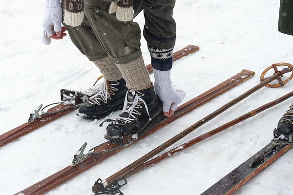 Ein Teilnehmer steigt beim Nostalgie-Skirennen in Winterberg-Neuastenberg in eine altertümliche Skibindung. - © Henning Kaiser/dpa