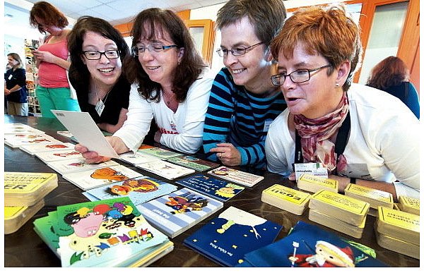 Maike Jenkel aus Norderstedt (Schleswig-Holstein), Ulrike Duss aus Bäch (Schweiz), Andrea Sippel aus Quelle und Claudia Busse aus Irland (v.l.) sehen sich gemeinsam neue Postkarten an, die sie bald verschicken wollen. - © FOTO: BARBARA FRANKE