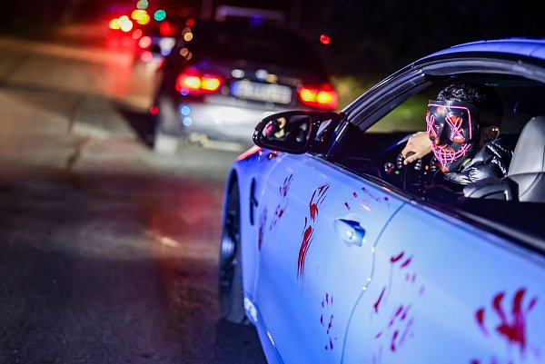 Illegales Tuningtreffen in Emmerich: Ein Mann mit Maske sitzt in einem Auto, auf dem mit roter Farbe Blutspuren aufgetragen sind. - © Christoph Reichwein/dpa