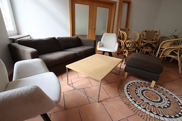 Hinten steht eine Sofaecke, daneben wird ein Spielbereich für Kinder eingerichtet. Noch stehen dort Stühle. - © Sigurd Gringel