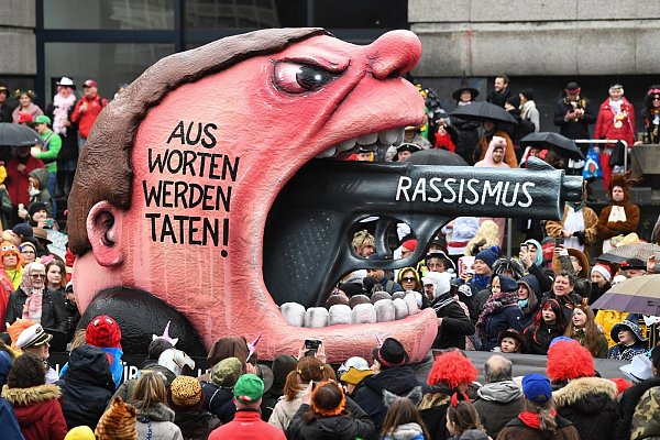 Düsseldorf: Ein Motivwagen "Rassismus - Aus Worten werden Taten!" mit einem aufgerissenen Mund, aus dem dem ein Pistolenlauf ragt, zieht beim Rosenmontagszug durch die Straßen. - © picture alliance/dpa