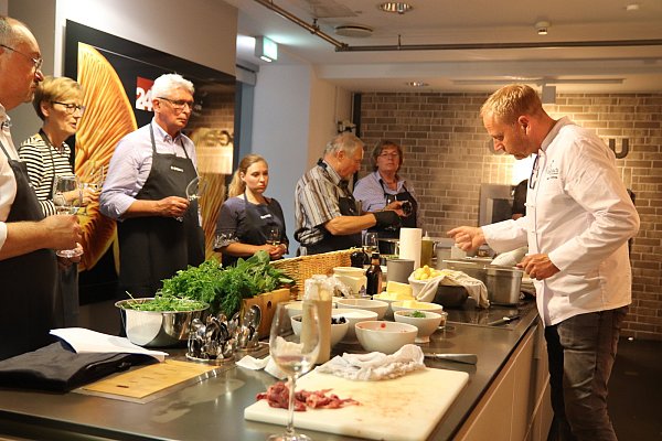 Koch und Restaurantinhaber Marc Höhne erklärt seinen zehn Kochkursteilnehmern, wie junge, gekochte Pellkartoffeln am besten zum gelingen. - © Alexandra Golfinger