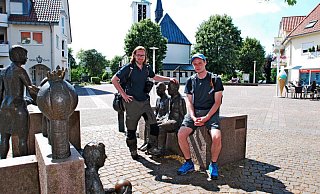 Rast auf dem Holter Kirchplatz: Tyler Larkin und Stefan Boes durchwandern Ostwestfalen-Lippe von Süden nach Norden. Gestern haben sie sich das Quellgebiet der Ems angeschaut und sind durch die Moosheide gewandert. - Gunter Held