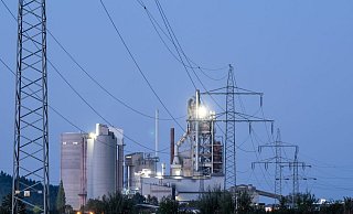 Strommasten stehen im Morgenlicht vor einem Zementwerk: Die Bundesregierung will den Strompreis für die Wirtschaft durch eine Steuerreform drücken senken. - Silas Stein/dpa