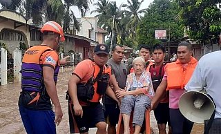 Eine ältere Frau wird von Mitarbeitern der Küstenwache in Sicherheit gebracht. - Uncredited/Philippine Coast Guard/AP/dpa