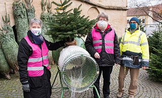 Pfarrerin Annette Beer, Pfarrer Johannes Beer und Presbyter Herbert Busch-Prüßing, einer der Ehrenamtlichen, die sich beim Verkauf engagieren, bieten Weihnachtsbäume für den guten Zweck an. - Ralf Bittner
