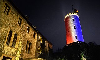 Bielefelder Anteilnahme: Seit Samstagabend leuchtet der Bielefelder Sparrenburgturm als Zeichen der Solidarität in den Farben der französischen "Tricolore". Die Deutschlandflagge oben hängt wegen des Volkstrauertages auf Halbmast. - Andreas Frücht
