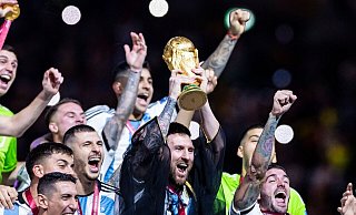 Argentiniens Lionel Messi jubelt mit WM-Pokal und seiner Mannschaft. Nun steht das Team auch auf Rang eins der Weltrangliste. - Tom Weller/dpa