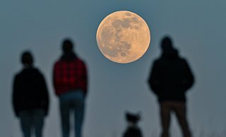 Menschen stehen auf einem Hügel und beobachten den aufgehenden Supermond. (Archiv) - dpa