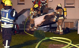Mannstark: Einsatzkräfte der Delbrücker Feuerwehr tragen an der Brandstelle in der Boker Königsalle den ausgebrannten Gefrierschrank ins Freie. - www.sportpictures.de