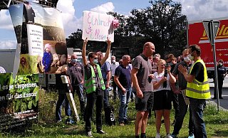 Jan Peifer vom Deutschen Tierschutzbüro (rechts, gelbe Weste) diskutiert mit Landwirt Burkhard Berg über das gezeigte Video. Im Hintergrund ist die Gegendemo der Bauern zu sehen. - Judith Gladow