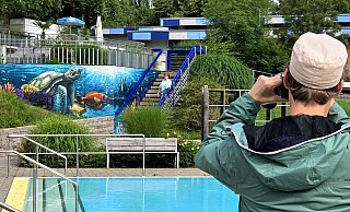 Denis Kelle fotografiert im Freibad Gadderbaum sein eigenes Werk - hinten freut sich Hannelore Pfaff mit ihm. - Kurt Ehmke