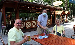 Schausteller Hans-Otto Bröckling (m.) serviert Oliver und Diana Meisehen Bier und Weinschorle bei sommerlichen Temperaturen. - Mareike Gröneweg
