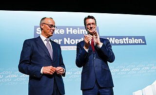 Bundeskanzler Friedrich Merz (l, CDU) steht nach seiner Rede beim Landesparteitag der CDU Nordrhein-Westfalen mit Hendrik Wüst (CDU), Ministerpräsident von Nordrhein-Westfalen, auf der Bühne. - Thomas Banneyer/dpa