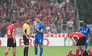 Schiedsrichter Michael Bacher (2.v.l.) muss das Spiel in Großaspach unterbrechen - Bernd Weißbrod/dpa