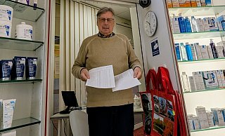 Apotheker Reinhard Rokitta steht vor seinem Beratungszimmer mit zwei Zetteln voller nicht verfügbarer Medikamente. Ersatz bekommt er, aber der Preis ist hoch. - Marek Schnelle