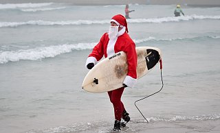 Events mit surfenden Weihnachtsmännern gibt es mittlerweile in mehreren Ländern. (Archivbild) - Ben Birchall/PA Wire/dpa