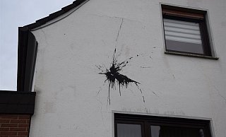 Einen großen schwarzen Fleck hat die mit Farbe gefüllte Christbaum-Kugel auf der Hauswand in Hiddenhausen hinterlassen. - Polizei Herford