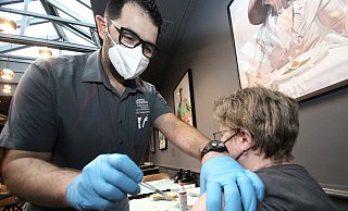 Regine Pfannkuche lässt sich vom Herforder Fußchirurgen Dany Lopes Ribeiro in einem Nebenraum des Restaurants eine Auffrischung-Imfung verpassen. - Peter Steinert