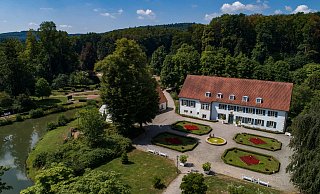 Touristisches Zentrum und Anlaufstelle: Das Haus des Gastes im Kurpark von Bad Holzhausen aus der Vogelperspektive. Hier erhalten Gäste Informationen über Übernachtungsmöglichkeiten, Sehenswürdigkeiten, Wanderrouten und vieles mehr. - Tourismus NRW e.V.