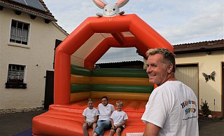 „Hüpfburg Happy“ steht in bunten Buchstaben auf dem T-Shirt-Rücken von Christian Tönnies. Seine „Klopfer“-Hüpfburg hat er in wenigen Minuten in der Garagenauffahrt aufgebaut – sehr zur Freude der Kinder Amelie und Marvin sowie Ehefrau Sonja. - Simone Flörke