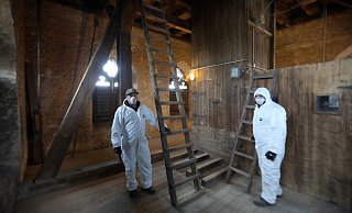 Enver Gevci und Andreas Ilmer stecken in den weißen Anzügen. Sie sind Mitarbeiter der der Evangelischen Diakoniestiftung und haben eine Woche lang den Taubenkot aus dem Glockenstuhl der Johanniskirche entfernt. - Frank-Michael Kiel-Steinkamp