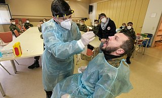 Der Gefreite Roman Spanberger (l.) übt den korrekten Rachenabstrich beim Oberstabsgefreiten Oleg Mast. Petra Dommasch vom DRK und die übrigen Soldaten schauen genau hin, ob das Stäbchen korrekt geführt wird. - Foto: Andreas Zobe/NW