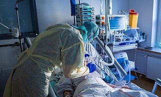 Ein Mitarbeiter richtet bei einer an Covid-19 erkrankten Patientin auf einer Intensivstation die Beatmungsmaske. - Symbolfoto: picture alliance
