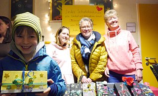 Nick (8) hat eine Schatztruhe mit bisher unbekanntem Inhalt erstanden. Im Hintergrund die stolzen Mitarbeiterinnen, Erzieherin Nicole Seniuch, Schulleiterin Bettina Wolff und Lehrerin Elke Schmidt. - Louisa Kohnert