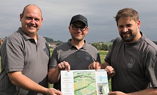 Marc Engemann (v. l.), Wilhelm Engemann und Thomas Fuest vom Festkomitee Ossendorf auf dem Festplatz mit einem Plan, der im Flyer zum Jubiläum enthalten ist. - Simone Flörke