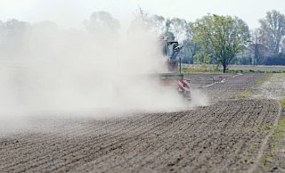 Ein Traktor wirbelt bei der Fahrt über einen Acker Staub auf. Auf vielen Äckern in OWL ist es derzeit staubtrocken.  - dpa