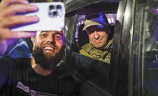 Jewgeni Prigoschin (r), Eigentümer des Militärunternehmens Wagner Group, sitzt in einem Militärfahrzeug und lässt ein Selfie mit einem Zivilisten auf einer Straße in Rostow am Don machen. - -/AP/dpa