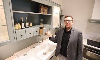 Tristan Beeck zeigt die "Romantik"-Küche im neuen Grünton Eukalyptus - sie hat wie früher Holzschütten integriert. - Nicole Sielermann