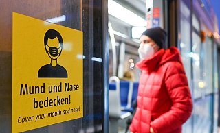 Eine Frau betritt mit FFP2-Maske eine Trambahn in München. - Tobias Hase/dpa