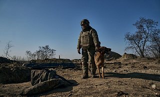 Ein ukrainischer Soldat steht mit seinem Hund an einem Graben in Bachmut. - Libkos/AP/dpa