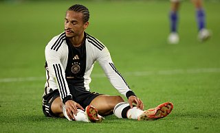 Leroy Sané sitzt nach der Niederlage gegen Japan enttäuscht auf dem Rasen. - Christian Charisius/dpa