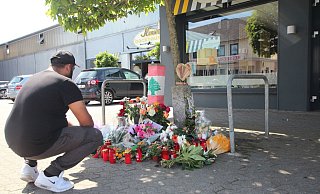 Freunde und Bekannte haben zum Gedenken weitere Blumen nahe des Tatorts abgelegt. Auch ein Foto, dass Ibrahim A. mit einem Rapper zeigt. Ein Freund des Opfers kniet vor den Blumen und Kerzen. Der junge Mann berichtet über den Toten. - Jobst Lüdeking