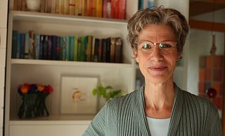 Ordnungsexpertin Ulrike Pieper steht vor ihrem Bücherregal, welches sie nach Farben sortiert hat. - Lena Kley