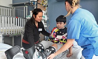 Der zehnjährigen Xandro trägt von einem Lkw-Unfall schwere Beinverletzungen davon. Phoebe Rubia, Chefin des Pflegeteams, (l.) hilft ihm in seinem neuen Zimmer ins Bett. - Barbara Franke