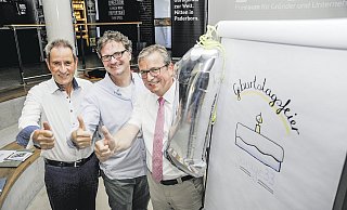 Drei Daumen, eine Kerze: Zum einjährigen Geburtstag der Garage 33 stellen (v. l.) Otto Drosihn (Vorsitzender von "Paderborn überzeugt"), Rüdiger Kabst (Leiter des Technologietransfer- und Existenzgründungscenters der Uni Paderborn) und Bürgermeister Michael Dreier ihr Foto zum Start des Innovationsquartiers nach. - Birger Berbüsse