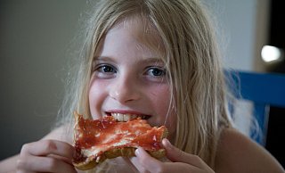 Ein Mädchen isst einen Marmeladentoast. - picture alliance / Caro