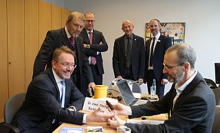 Georg Backhausen misst bei Volker Böttcher, Vorstand der Sparkasse Minden-Lübbecke die Blutwerte. Paul Gauselmann (v. l.), Peter Schellinger, Karl-Friedrich Rahe (stellv. Lübbecker Bürgermeister) und ?Stefan Kröger (stellv. Leiter der Geschäftsstelle Lübbecke) schauen interessiert zu. - Klaus Frensing