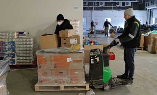 Mit elektrisch betriebenen Hubwagen werden die Waren aus den Hövelhofer Lkw ausgeladen. Organisator Christian Bökamp (l.) hat die Abläufe im Blick. In Polen werden alle Hilfsgüter und Organisationen registriert. - Raphael Athens