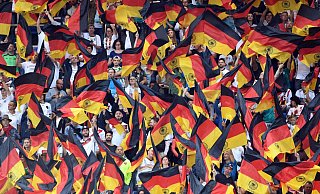 Fans schwenken Deutschlandfahnen auf der Tribüne. - Uli Deck/dpa