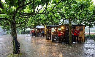 Zumindest ein bisschen Schutz: Fussballfans in Dortmund haben sich beim strömenden Regen an Imbissbuden untergestellt. - Christoph Reichwein/dpa