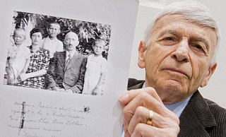 Kommt als Zeuge zum Auschwitz-Prozess: Der KZ-Überlebende Max Eisen, der auch gegen den ehemaligen SS-Wachmann Oskar Gröning in Lüneburg aussagte, hier im Lüneburger Gerichtssaal im April 2015 mit einem Foto seiner Eltern und Geschwister aus dem Jahr 1940. Er selbst ist der Junge, der hinter den Eltern steht.   - picture alliance / dpa