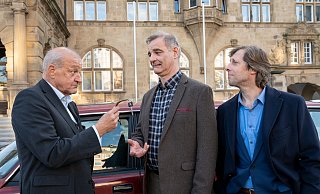 Im Hintergrund der Schlüsselübergabe von Georg Wilsberg (Leonard Lansink, l.) an seinen Freund Manni Höch (Heinrich Schafmeister, Mitte) prangt die Fassade des alten Bielefelder Rathauses. Rechts Kumpel Ekki (Oliver Korittke). - ZDF/Thomas Kost