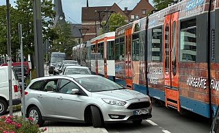 Die Autos fahren vom Parkplatz auf Straße und Gehsteig an der Bahn vorbei. - privat