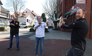 Nehmen die Krise mit Humor: Die Friseure Marko Windmann (v. l.), Bernd Ritter und Stefan Schwarze posieren mit schön viel Abstand zueinander. Um die zwei Meter Abstand zu symbolisieren, hat Ritter kurzerhand sein Handwerkszeug getauscht. Statt einer Friseurschere kommt der Rasentrimmer zum Einsatz. - Susanne Barth
