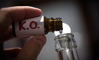 Ein Mann füllt in der gestellten Szene mehrere "K.O. Tropfen" in eine Bierflasche. - Nicolas Armer/dpa